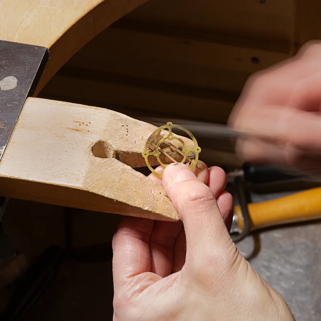 Hand van de maker aan het vijlen in het proces van het maken van een broche